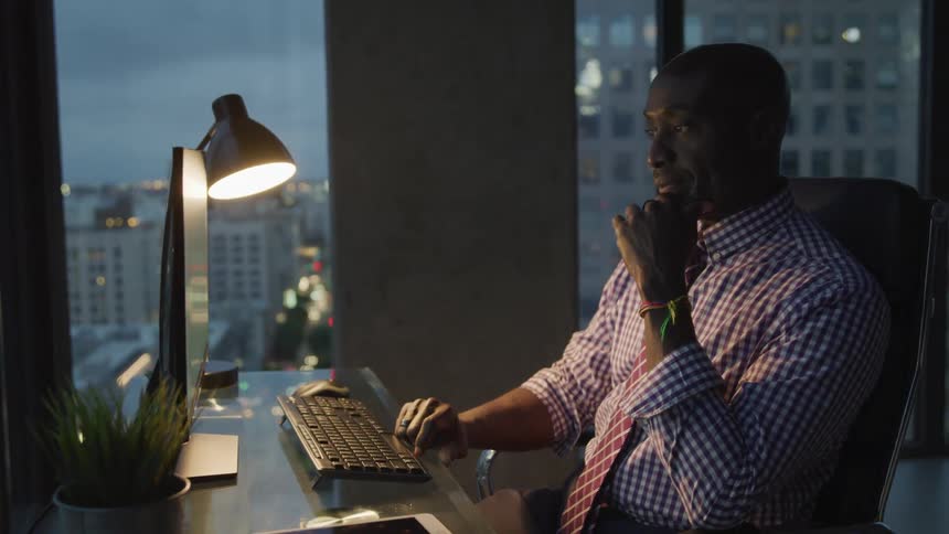 A man sits at his desk and works on his computer
