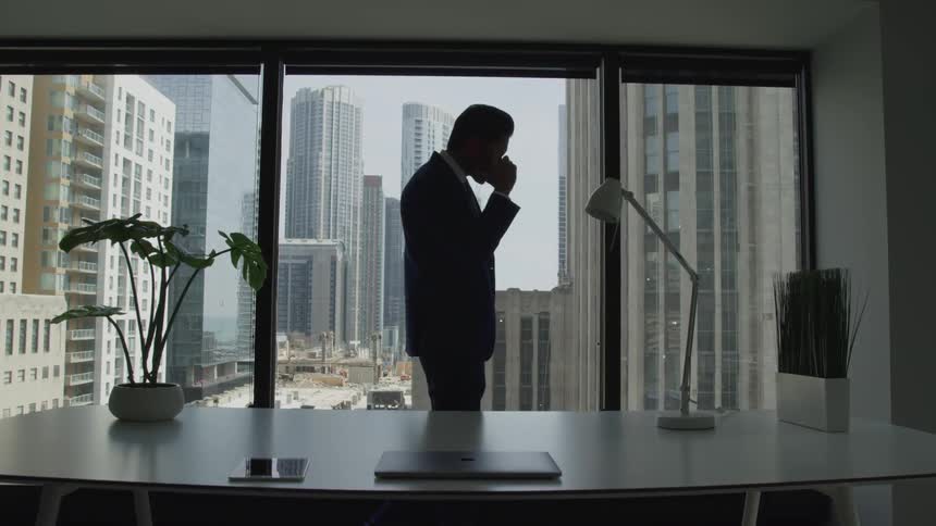 A man is talking on his phone and walking in his office