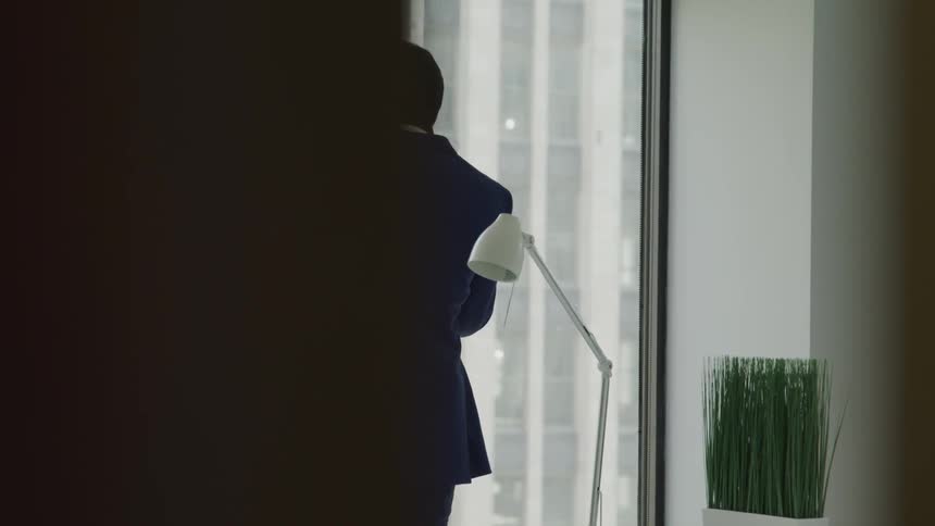 A businessman talks on his smartphone and paces in his office