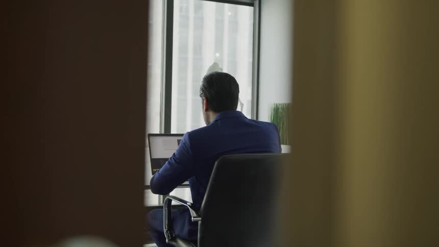 A man sits at a desk working on a laptop