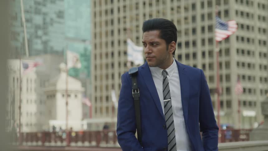 A man with a suit and tie standing up with buildings in the background
