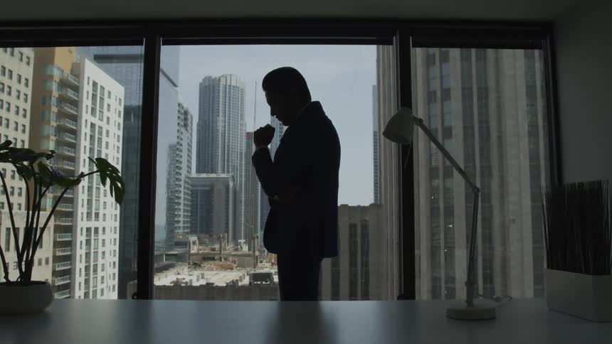 Businessman silhouette stands immersed in thoughts in the office