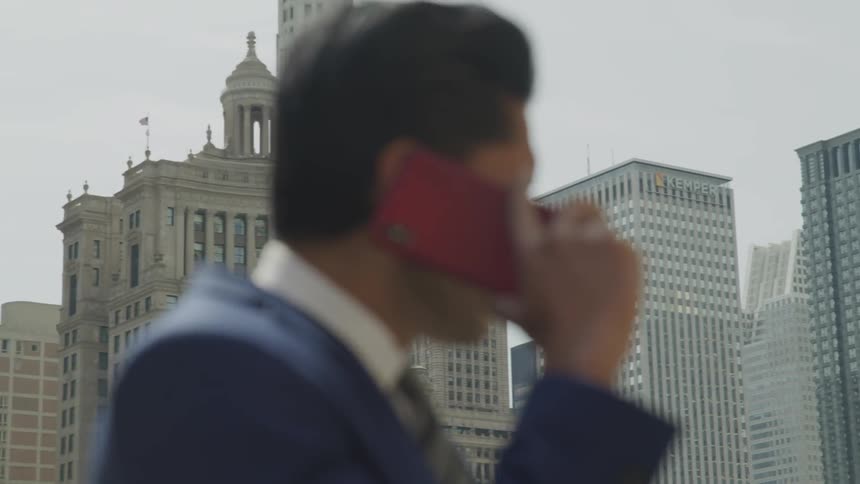 A man on a red phone in the downtown area of a large city