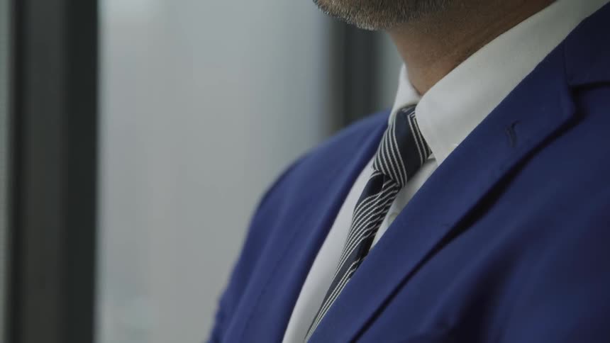 A man wearing a suit and a tie stands still