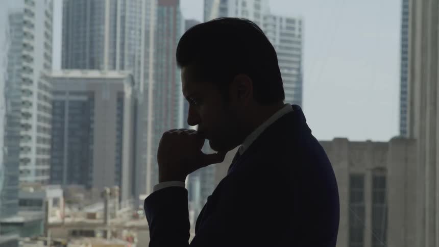 Businessman silhouette stands immersed in thoughts in the office