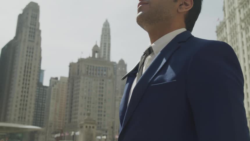 A man stands outside and looks up a the skyscrapers