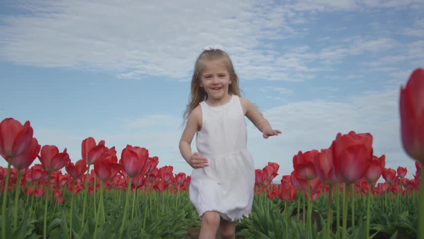 A girl running outside through a field of flowers