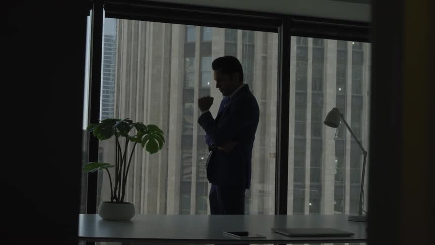 A man is standing in an office by the window