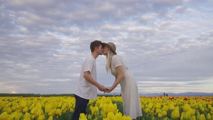 Two people kiss in the field of flowers