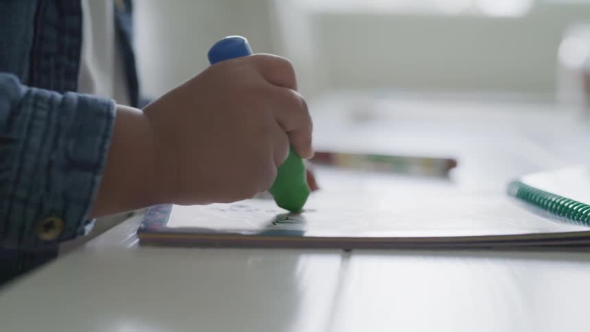 A child uses a fat green and blue brush on a sketch pad
