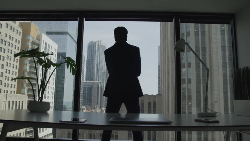 Businessman silhouette stands immersed in thoughts in the office