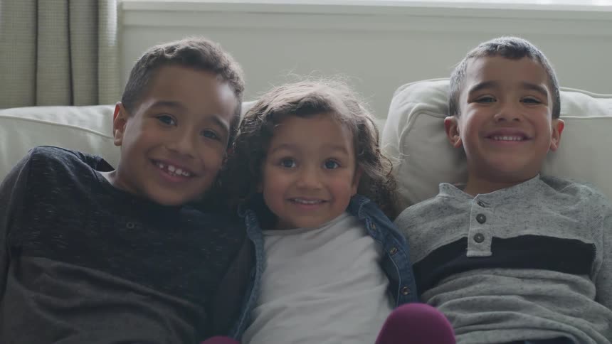 Three kids sit together on a couch