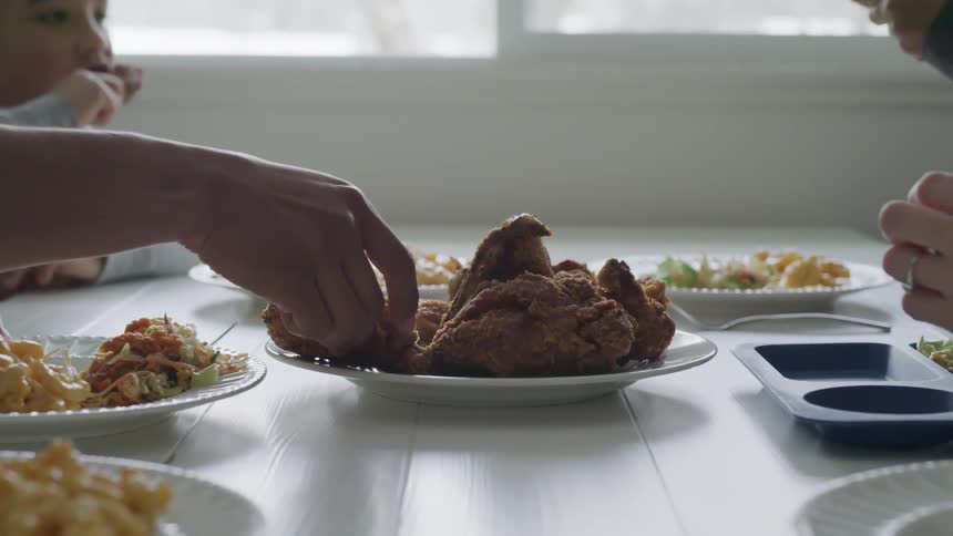People grab for the chicken on the table