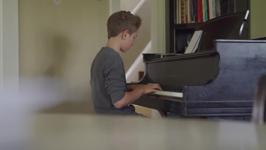 A boy plays a piano at home