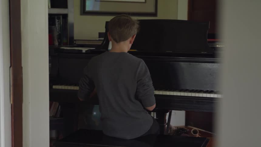 A young boy plays the piano