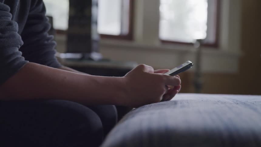 A boys sits and scrolls through his phone