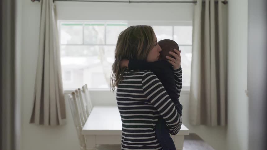 A young woman holds a baby close to her