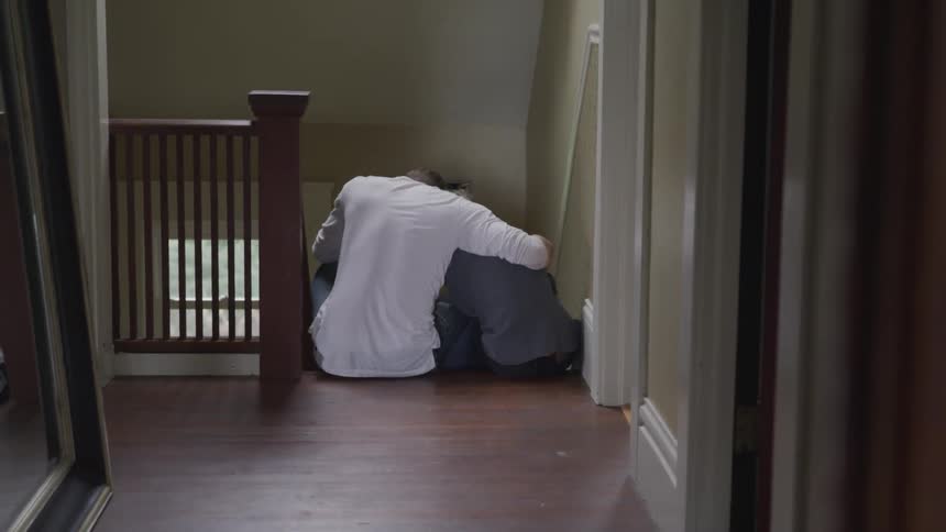 A dad hugs and comforts his son as they both sit on the top step of the second floor landing
