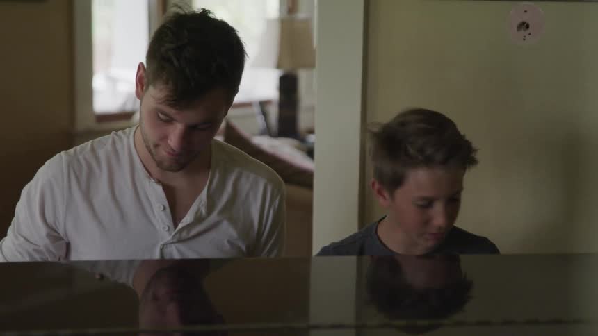 A father and son play the piano together