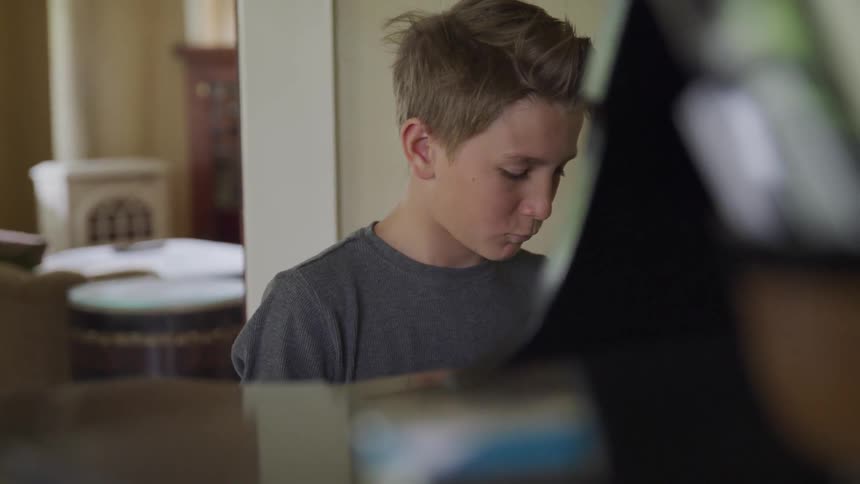 A boy plays at the piano