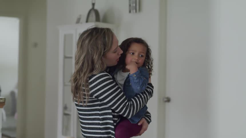 A woman is carrying her child in the living room