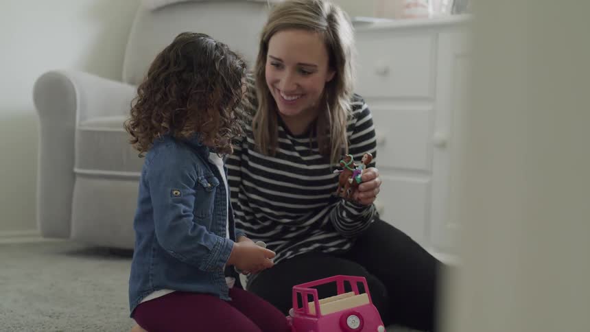 A woman and her daughter play with toys