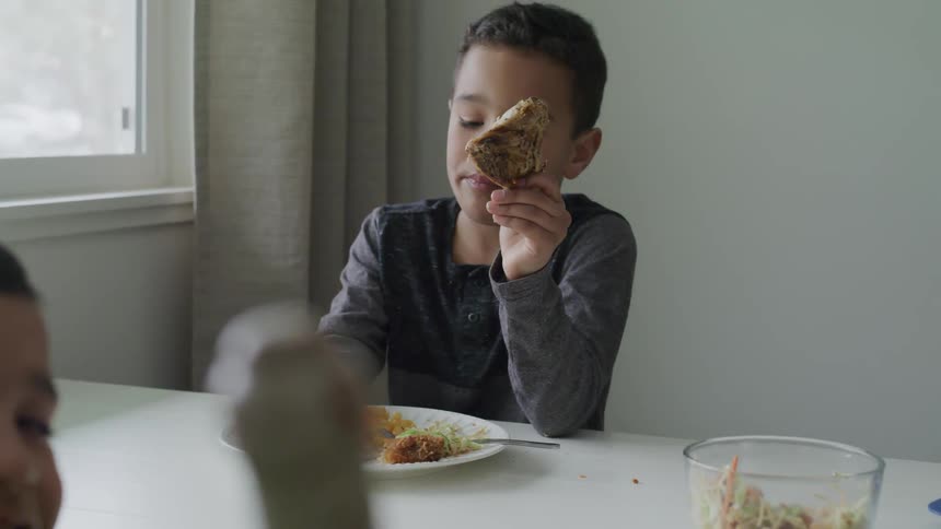 A young boy takes a bite from a carrot and puts it back on his plate