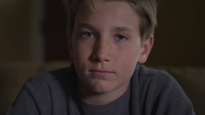 White boy looks at the camera and blinks in a room