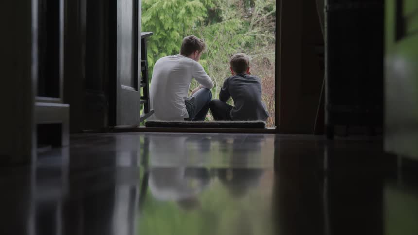 Father and son are sitting outside of their house