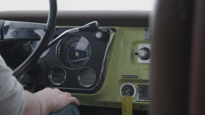 A man drives a vintage truck with a green colored dashboard