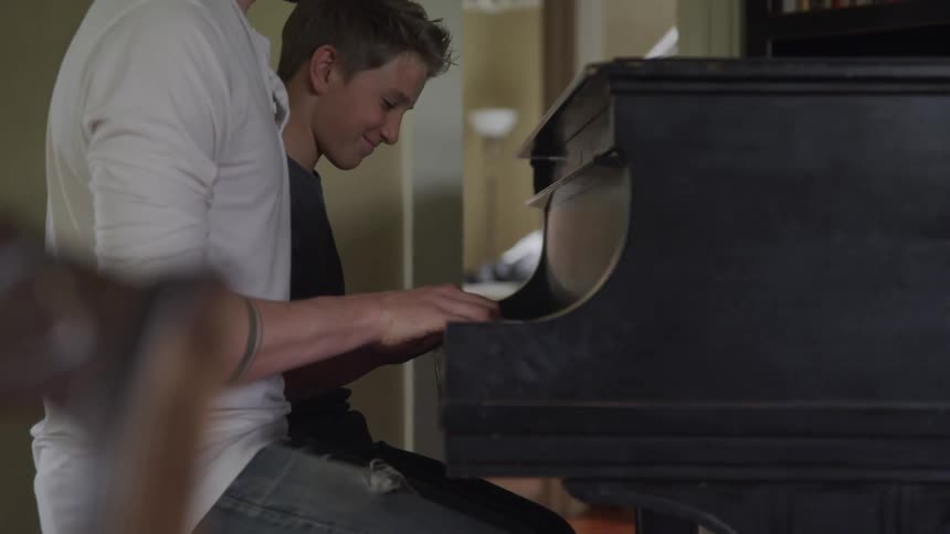 Man and boy plays the piano together indoors