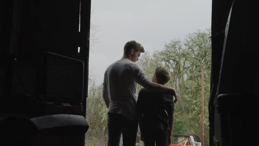 A father and son stand by the barn door