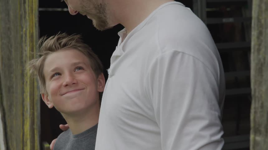 A young boy looks ups at his dad and smiles