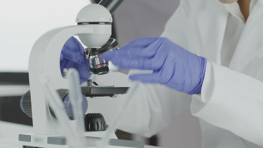 A woman is looking at something under a microscope