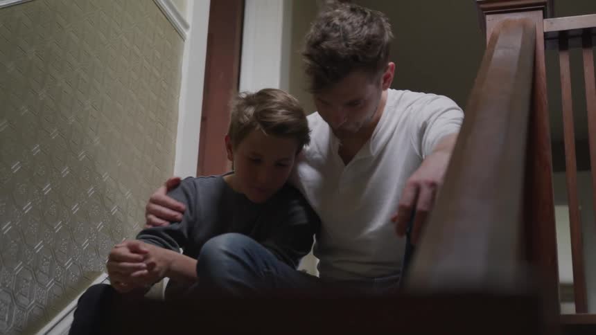 A man and a boy sitting on a staircase talking