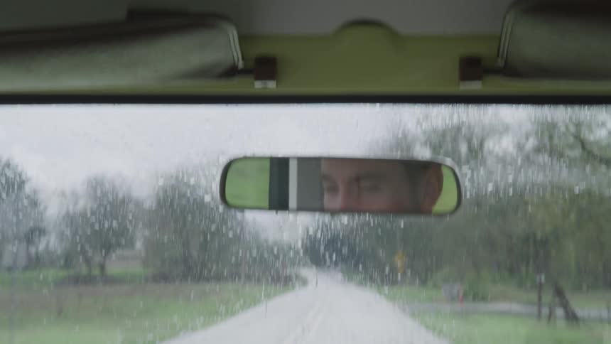 A man is driving a vehicle in the rain