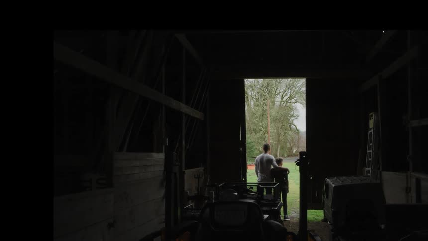 A young boy and his dad stand in a doorway of a shop and look outside