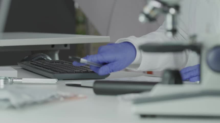 Hand with gloves typing on the computer keyboard