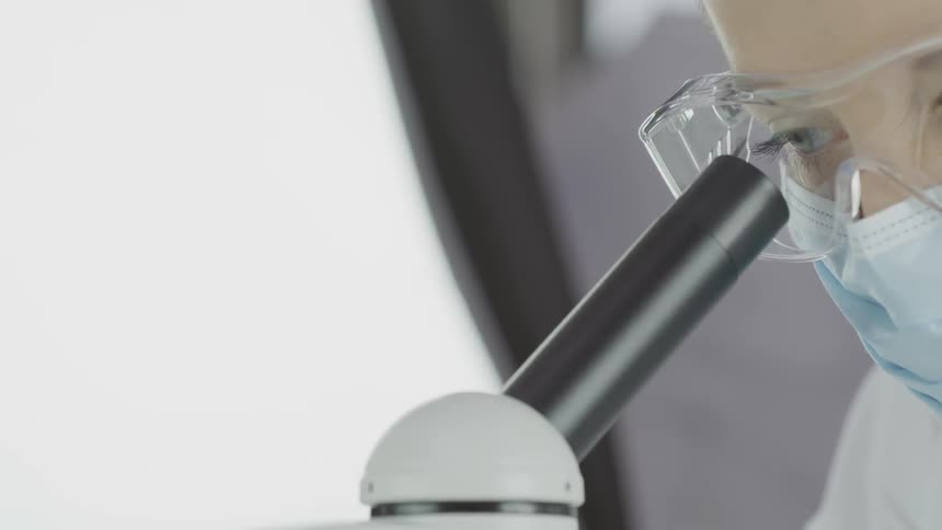 A woman looks in to a microscope