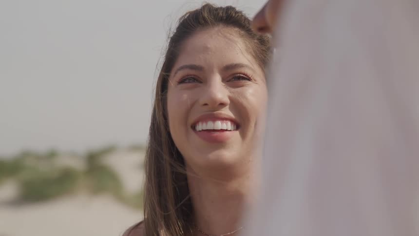 White woman looks at the black woman and laugh together on the beach during the daylight