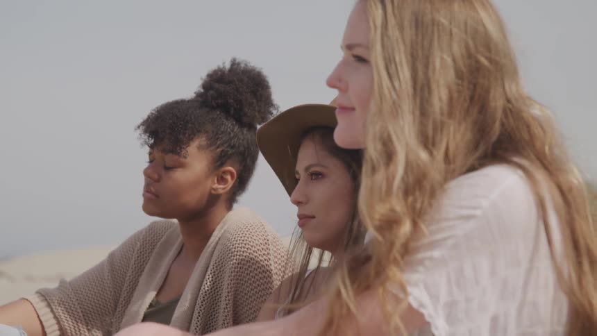 Three woman are sitting at a beach together
