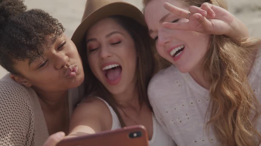 Three girls take pictures on a phone