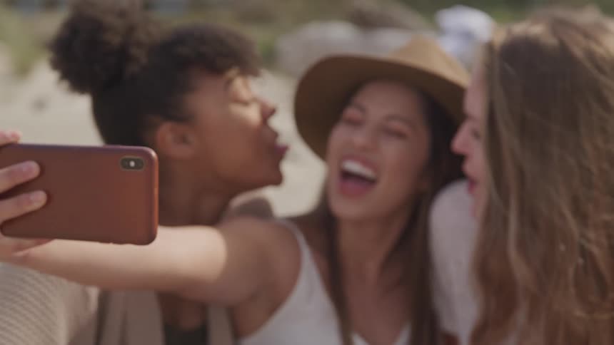 Three girls smile for selfies