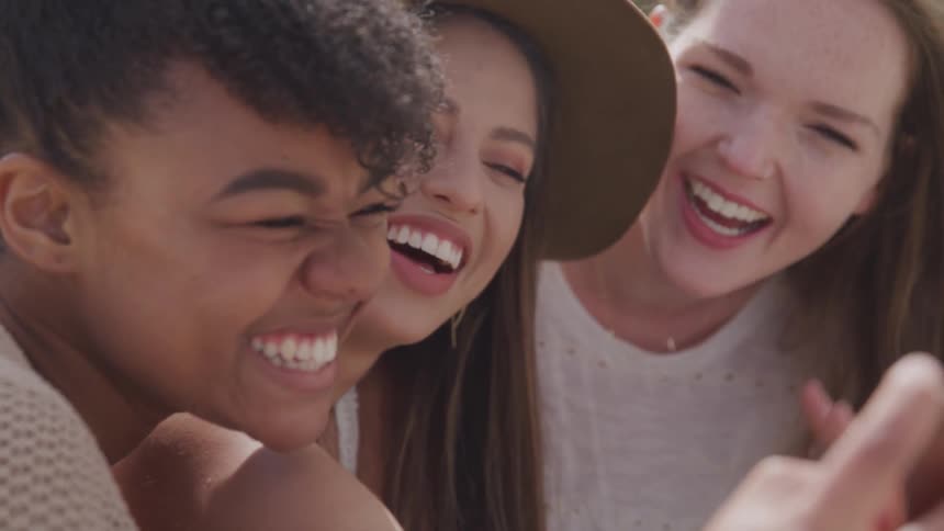 Three teenagers laugh together and take a selfie
