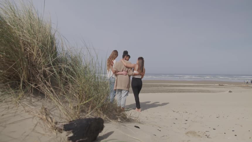 A group of women hugging on the beach coastal