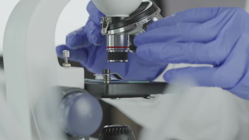 Lab worker adjusts the controls on a microscope