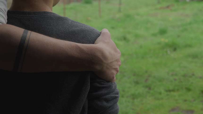 A father has his arm around his son while standing outdoors