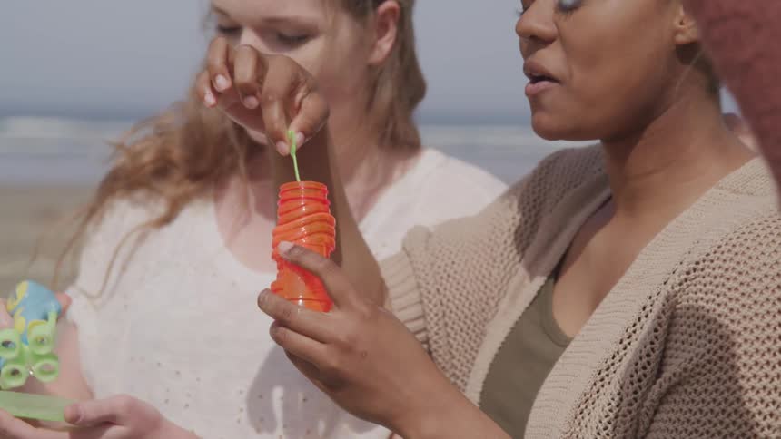 Three woman are blowing bubbles outdoors and having fun