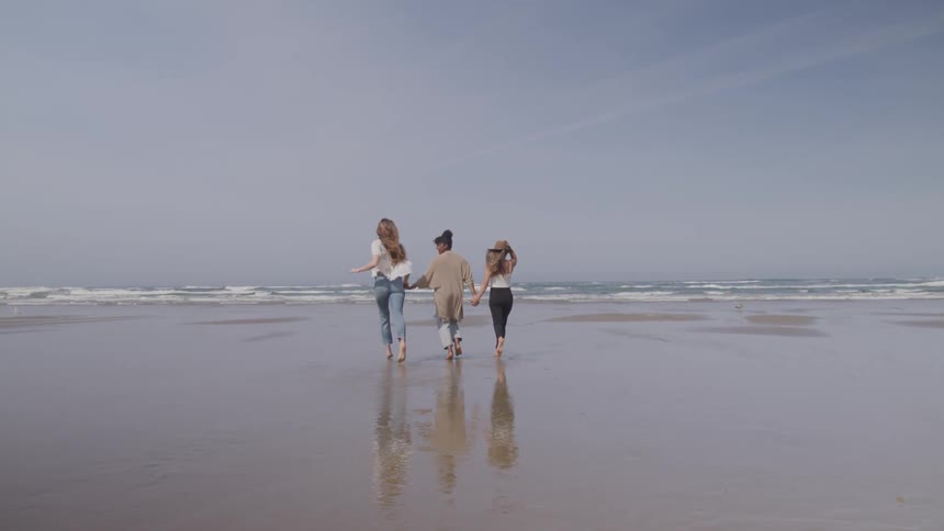 Three girls jog on the beach