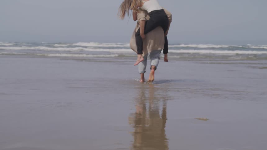 A woman is being carried by a man on the beach